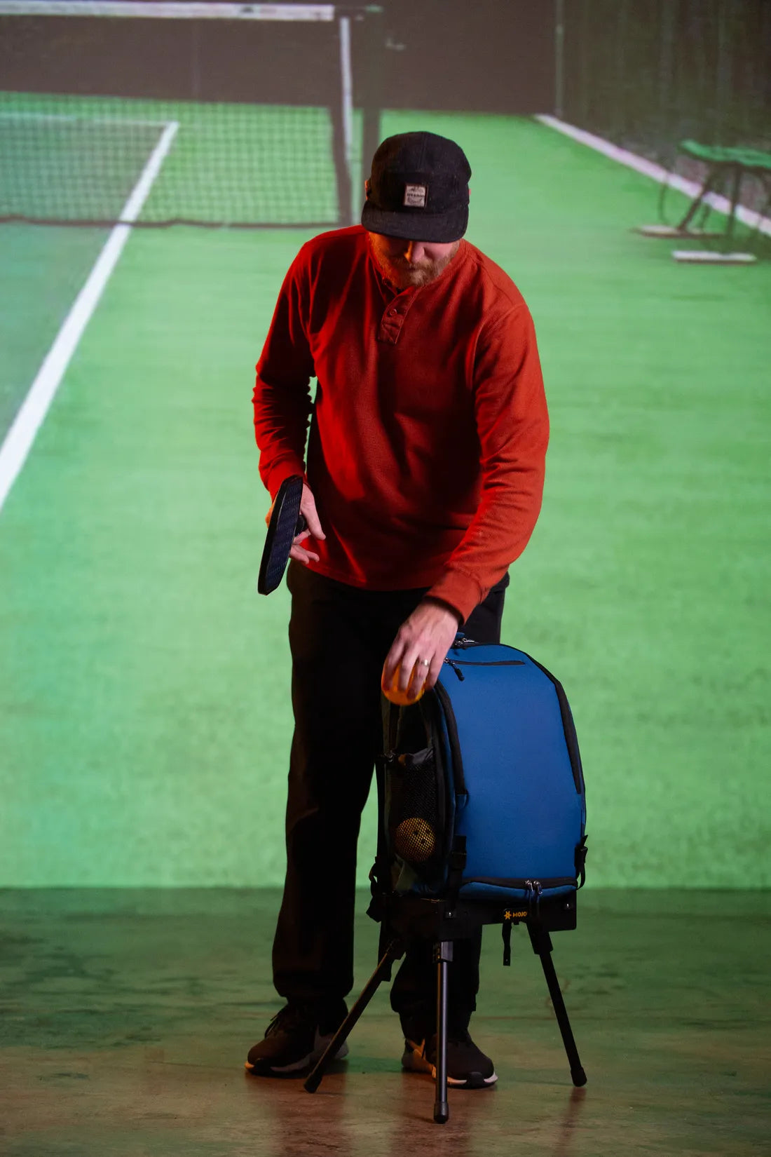 A pickleball player with a paddle and a gear bag held upright on the Ryzer Go at the court